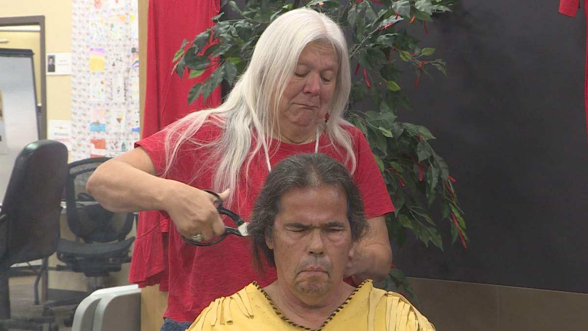 David Ladouceur (front) gets his hair cut by community elder Geri Musqua-LeBlanc (back) in a deeply personal ceremony honouring MMIWG.