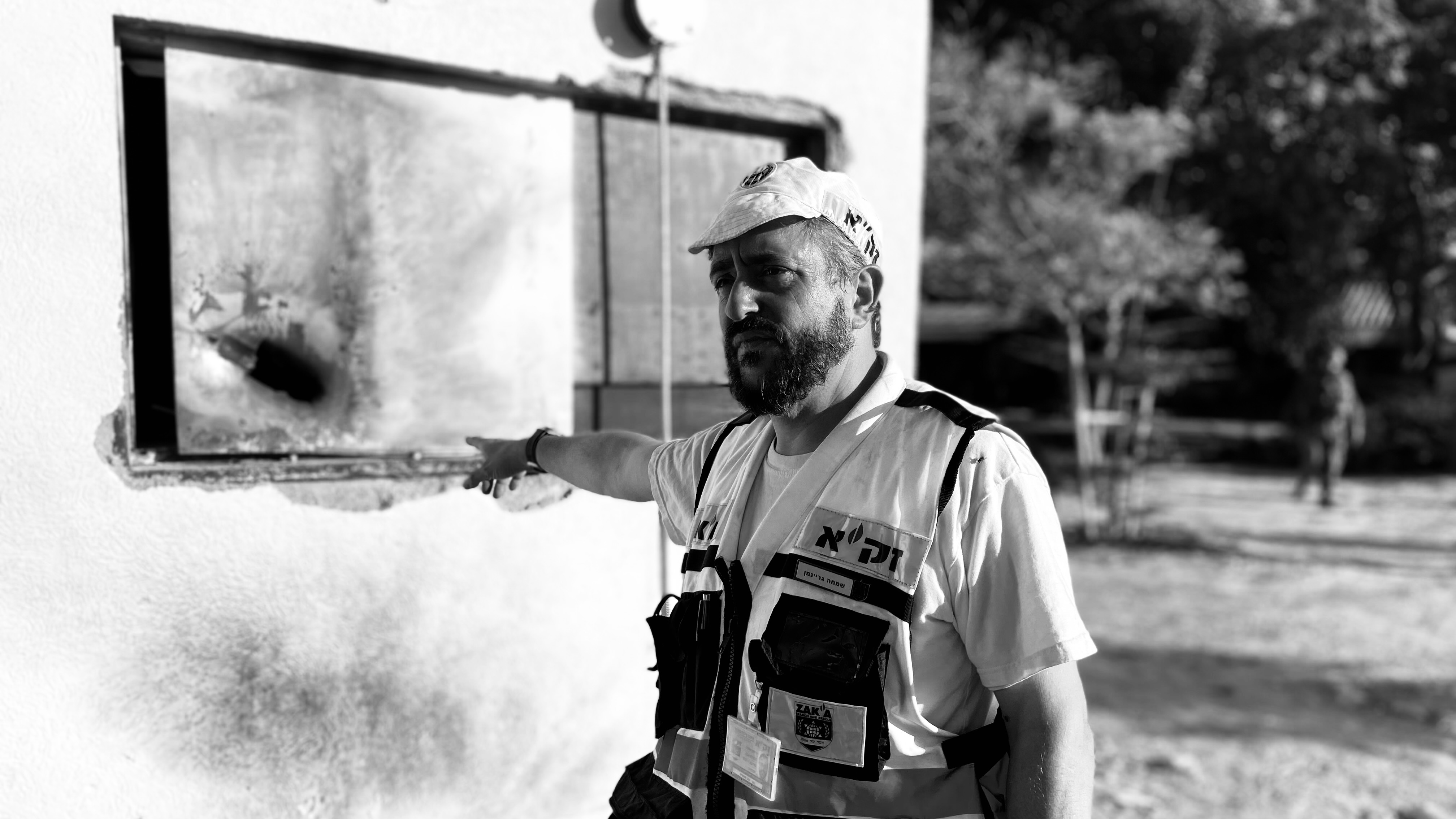 A Zaka volunteer points to the window where a rocket-propelled grenade struck the home of Moshe Ridler on Oct. 7.