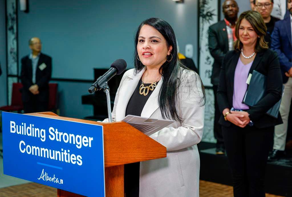 Minister Rajan Sawhney speaks at an announcement as Alberta Premier Danielle Smith looks on in Calgary, Alta., Friday, April 14, 2023. The Alberta government is proposing changes to a tech job title to help make it easier for tech firms to recruit workers.