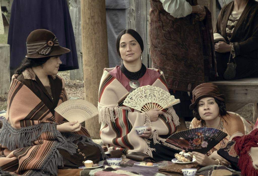 A group of people sit at a table with fans and blankets