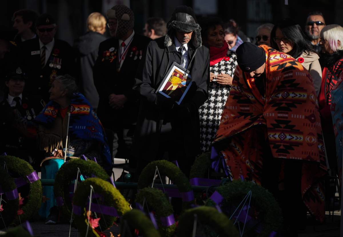 A group of people gather by wreathes