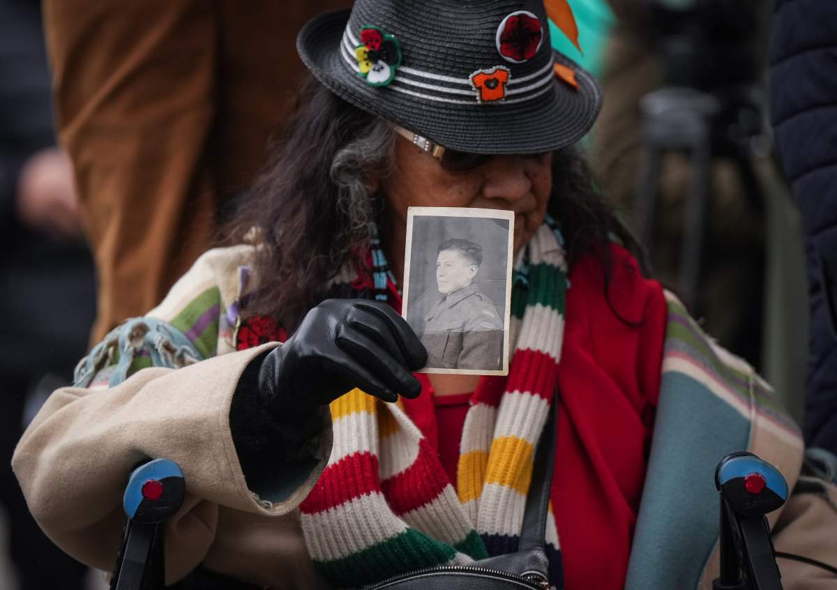 A woman with long hair holds a photo of her late great uncle