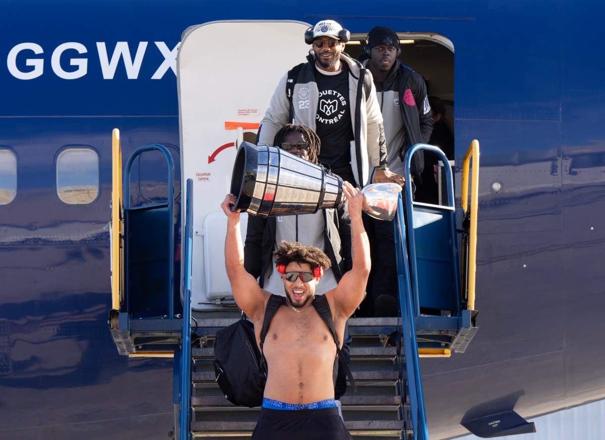 Montreal Alouettes’ Mustaffa Johnson lifts the Cup as the team arrives at Mirabel airport after wining the Grey Cup, in Mirabel, Que., Monday, Nov. 20, 2023.