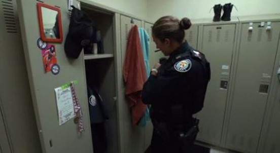 A police woman stands at a locker.