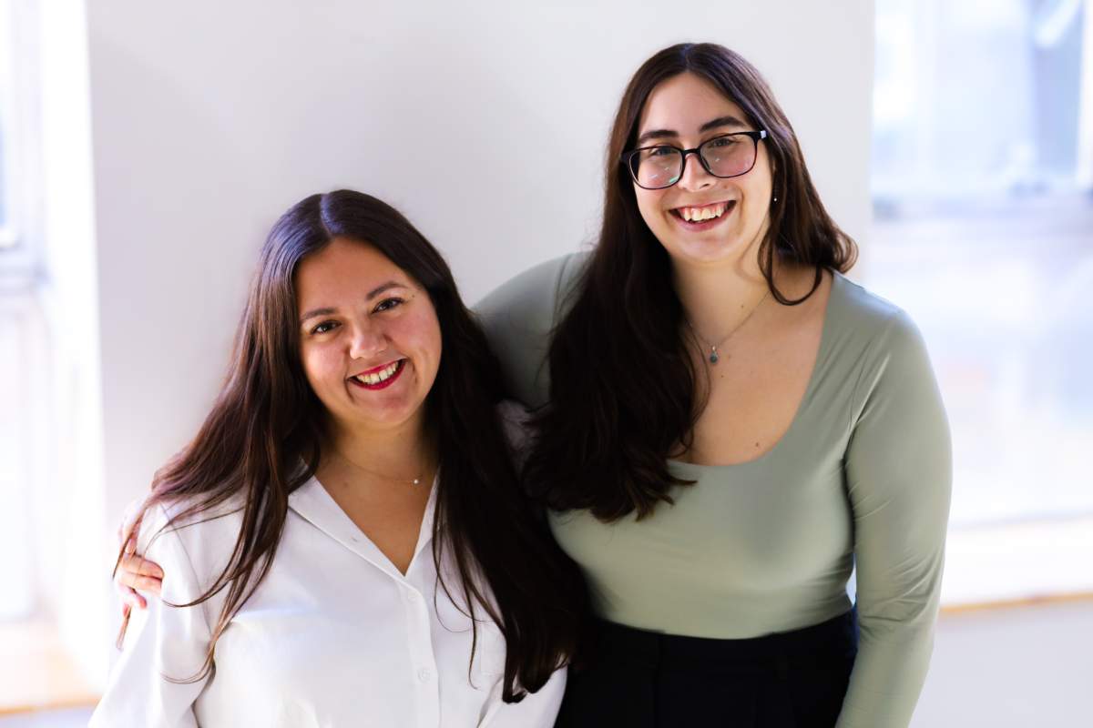 Two people pose for a photo. They both have long brown hair