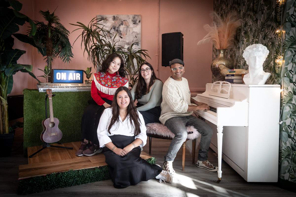 A group of people pose for a photo by a white piano