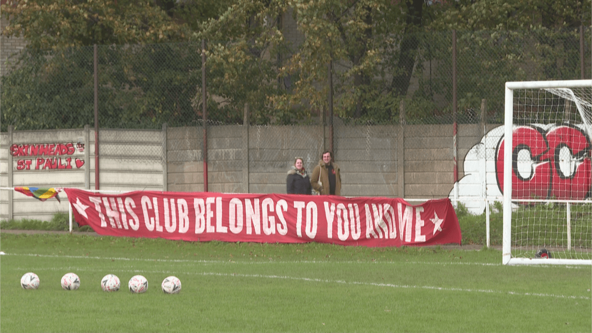 A banner says "This Club Belongs to You and Me" at the Old Spotted Dog Stadium in London, England.