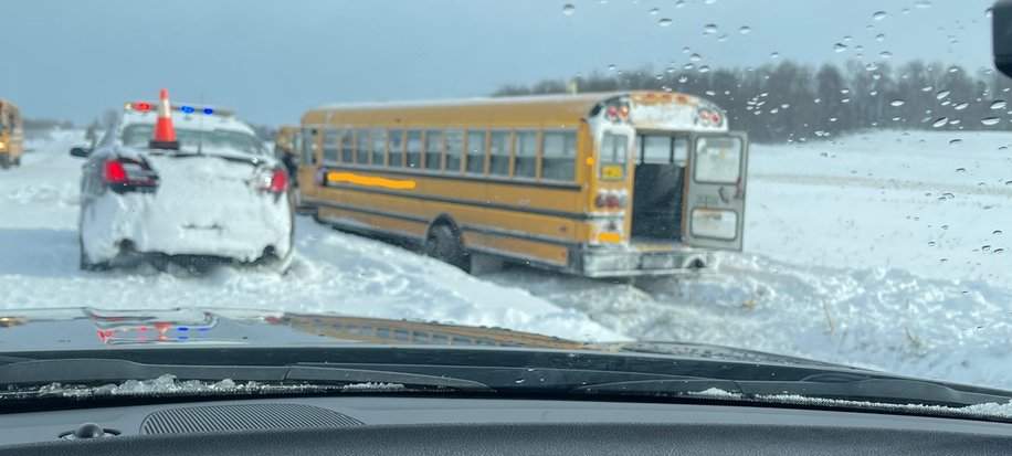 A school bus off to the side of a snow-covered road.