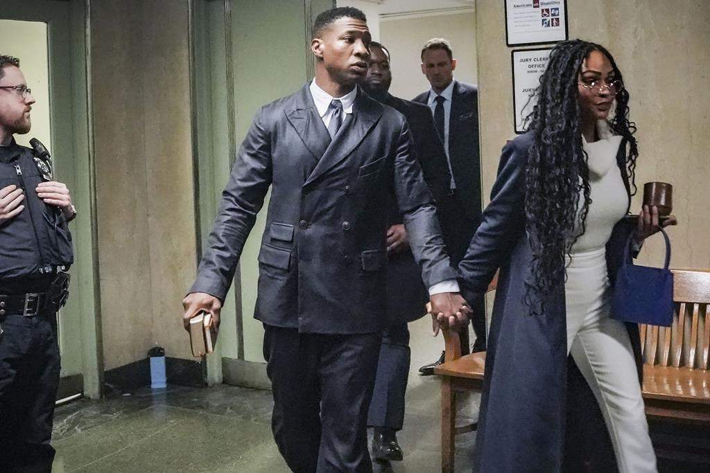 Jonathan Majors, center, and Meagan Good, right, hold hands as he returns to the courtroom, during jury deliberation in his sexual assault case, Friday Dec. 15, 2023, in New York.