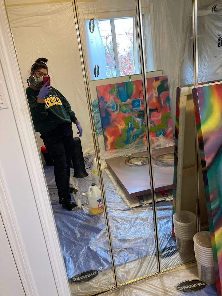 Woman stands next to art piece she created