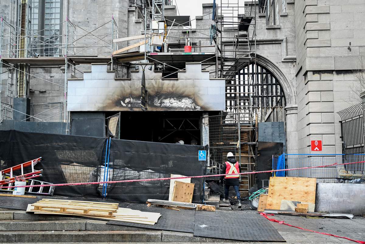 A construction worker walks through the scene at the Notre Dame Basilica in Montreal, Sunday, Dec. 24, 2023, after a fire at the historic site. Police say arson investigators were at the scene this morning and determined the fire’s origin was electrical.
