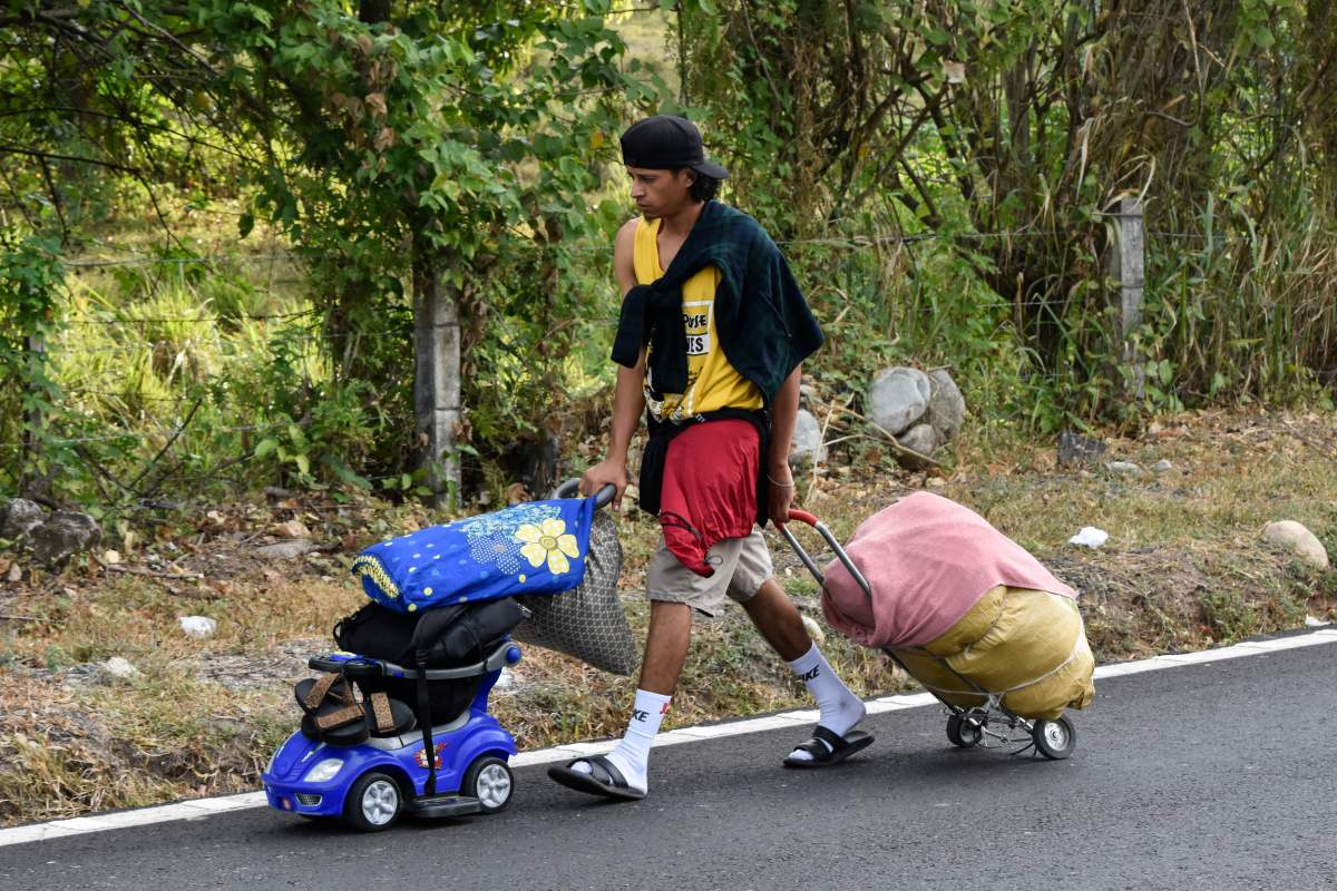 A migrant pushes and pulls his family’s belongings as he walks north with a migrant caravan on the side of the highway in Villa Comaltitlan, Chiapas state, southern Mexico, Wednesday, Dec. 27, 2023. (AP Photo/Edgar H. Clemente)