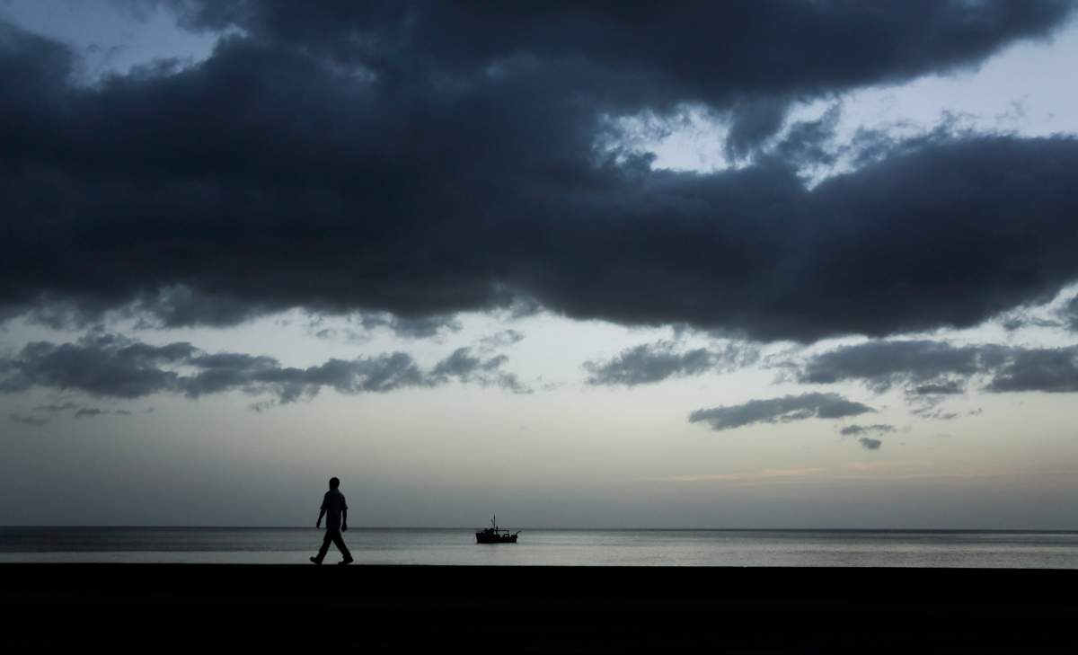 A man walks on the seawall bordering the coastline in Roseau, Dominica, on June 6, 2015. Daniel Langlois and Dominique Marchand ‘fell in love with the island’s natural beauty.’