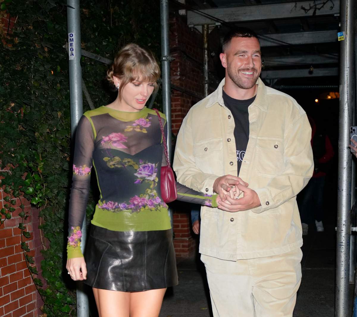 Taylor Swift and Travis Kelce. They are holding hands.