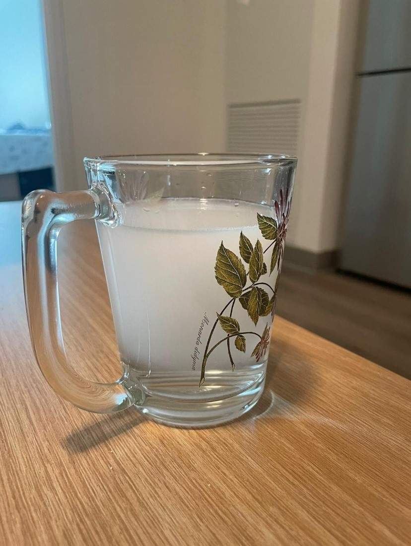 A photo of a glass of water, but the water isn't clear - it has an almost milky-white colouring to it.