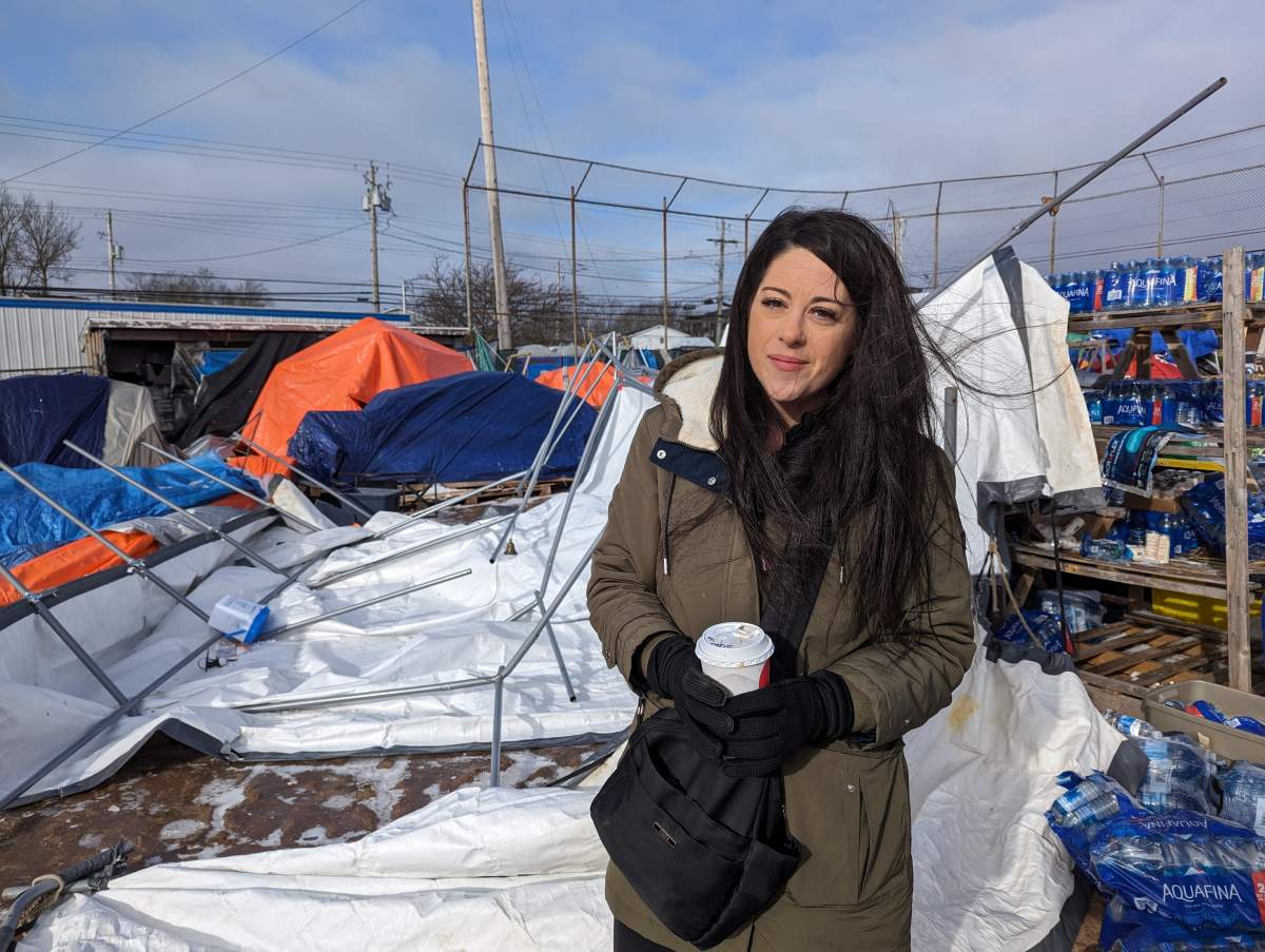 Nikki Greer, president of the Gated Community Association, stands in front of a food tent destroyed by high winds.
