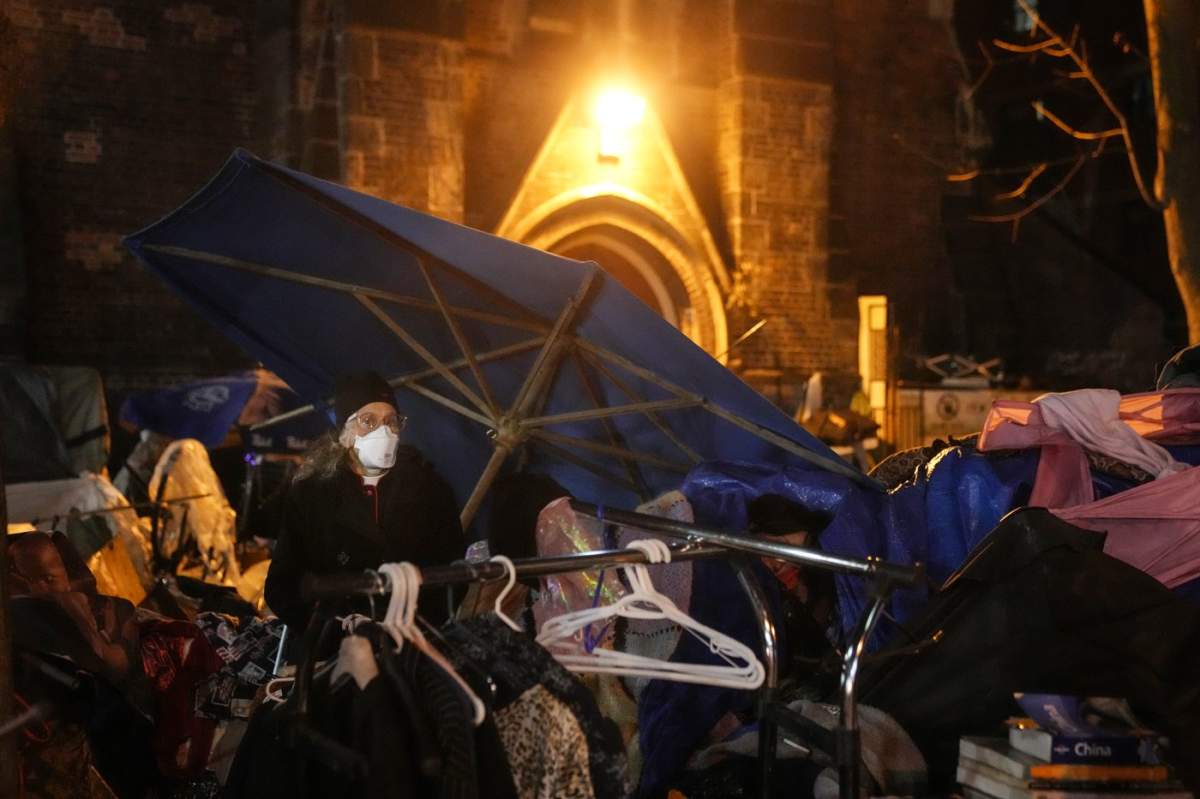 Rev. Canon Maggie Helwig stands guard over a remaining encampment resident (obscured) at the tented community outside of the St. Stephen-In-The-Fields Anglican Church in Toronto on Friday Nov. 24, 2023, as the City of Toronto begins to clear out an encampment in Kensington Market. 