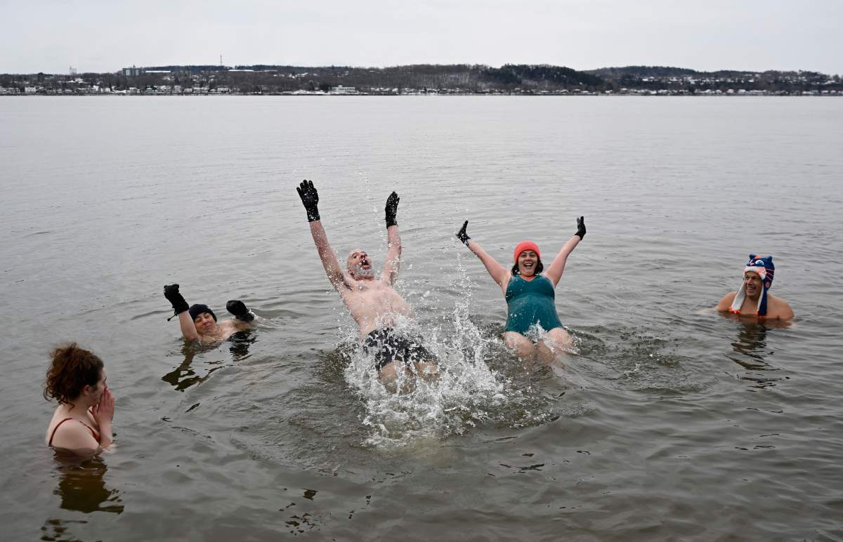 Francis Vachon, centre and Florence Auger, right, plunge backward into the ice cold water of the St.Lawrence River for a New Year’s Day polar bear swim, Monday, Jan. 1, 2024 in Quebec City. THE CANADIAN PRESS/Jacques Boissinot