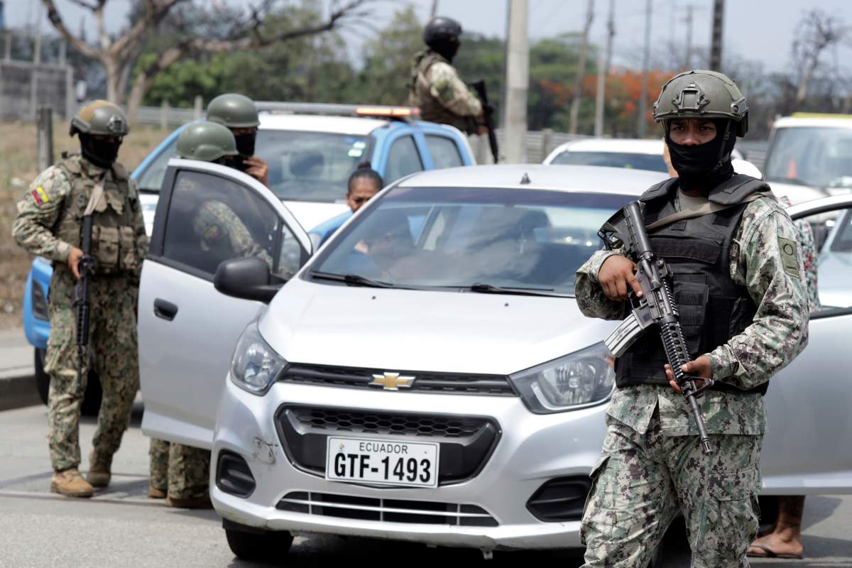 Soldiers check for weapons at a check-point on a north-bound highway in Guayaquil, Ecuador, Wednesday, Jan. 10, 2024. The government has said at least 30 attacks have taken place since authorities announced that Los Choneros gang leader Adolfo Macías, alias Fito, was discovered missing from his cell in a low-security prison Sunday. (AP Photo/Cesar Munoz)