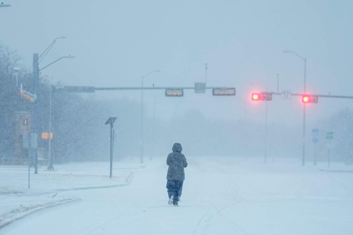 A jogger trots on a snow-covered road during a winter storm, Monday, Jan. 15, 2024, in Grand Prairie, Texas. (AP Photo/Julio Cortez)