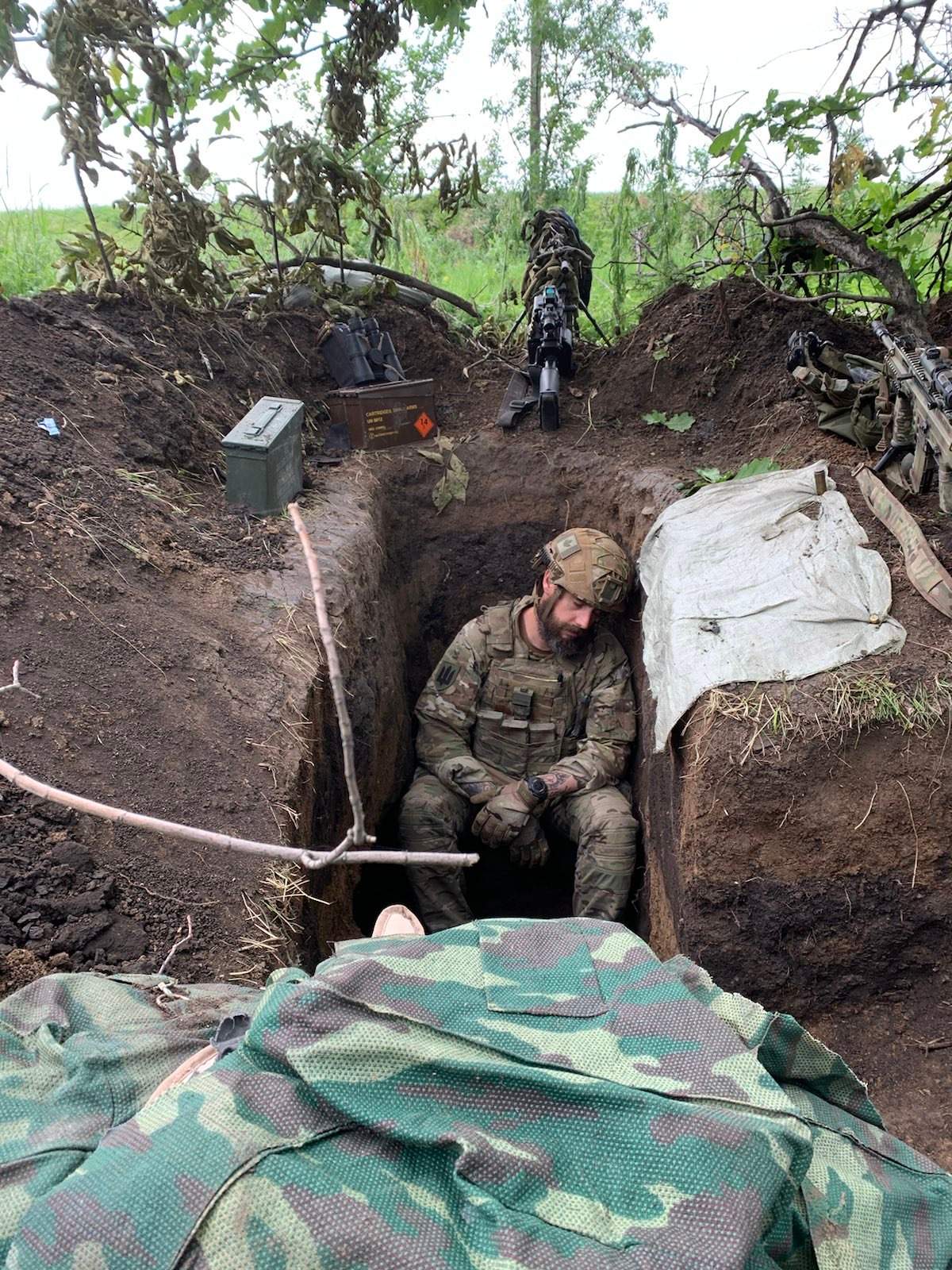 A solider takes a nap while seated in a 1-metre deep trench.