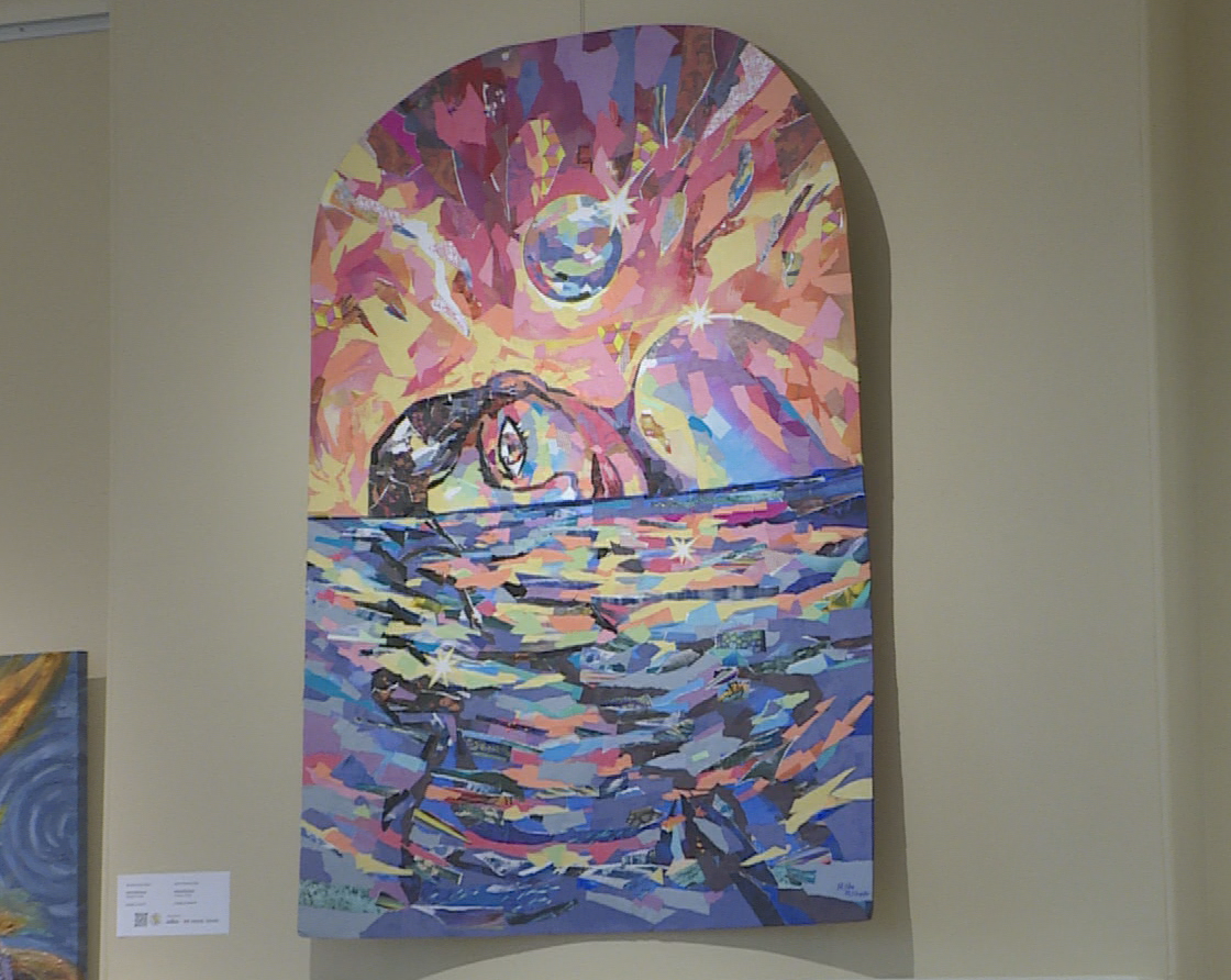A painting of a woman lying in water with a red sky and a ball coming toward her.