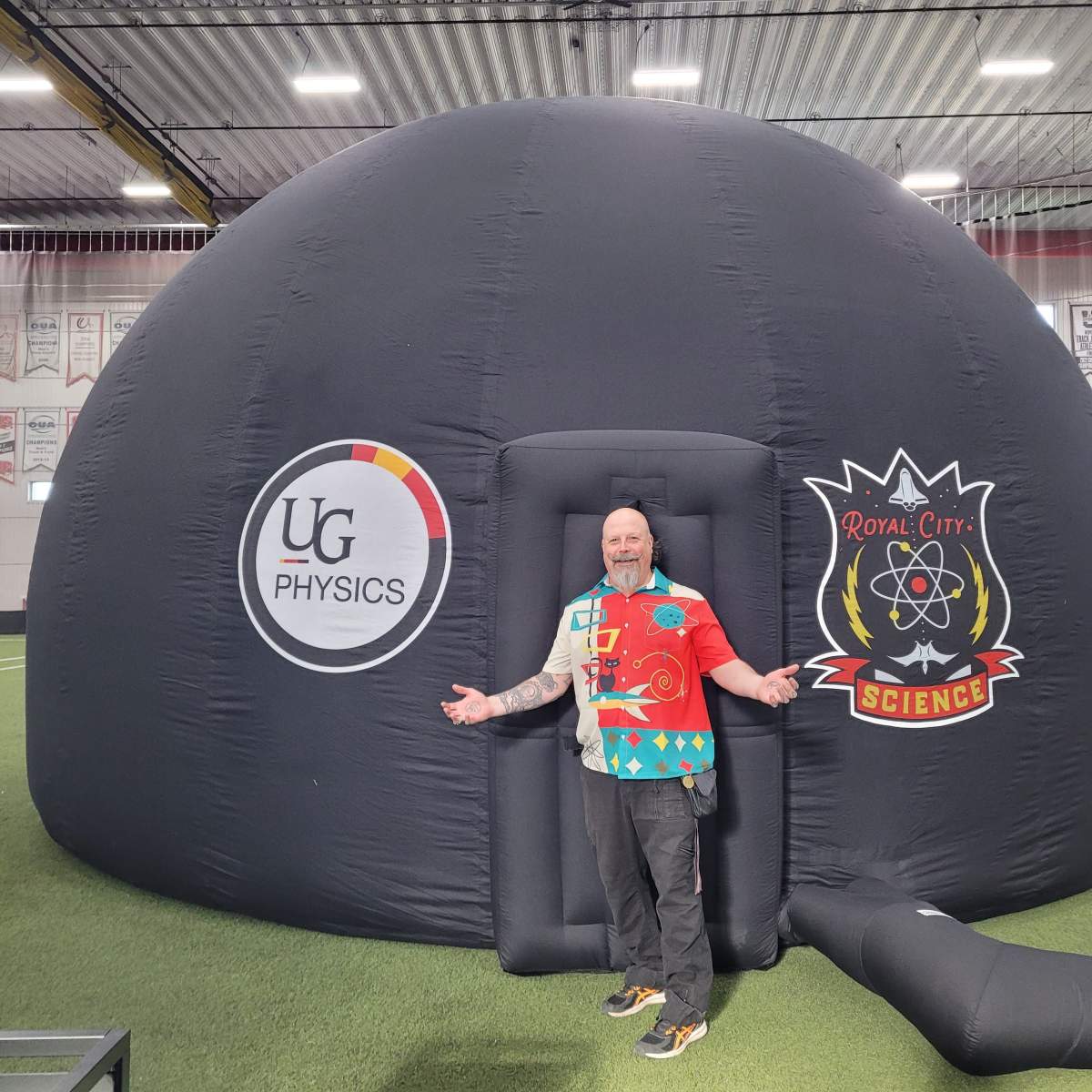 Orbax of Royal City Science stands in front of a portable planetarium.
