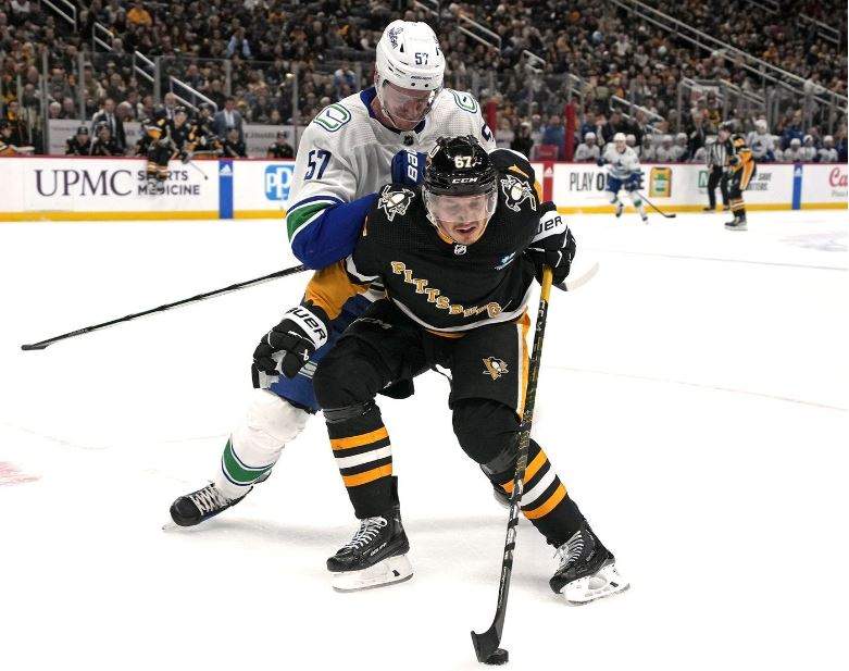 The Pittsburgh Penguins’ Rickard Rakell (67) works to control the puck with the Vancouver Canucks’ Tyler Myers defending during the second period of an NHL hockey game in Pittsburgh, Thursday, Jan. 11, 2024.