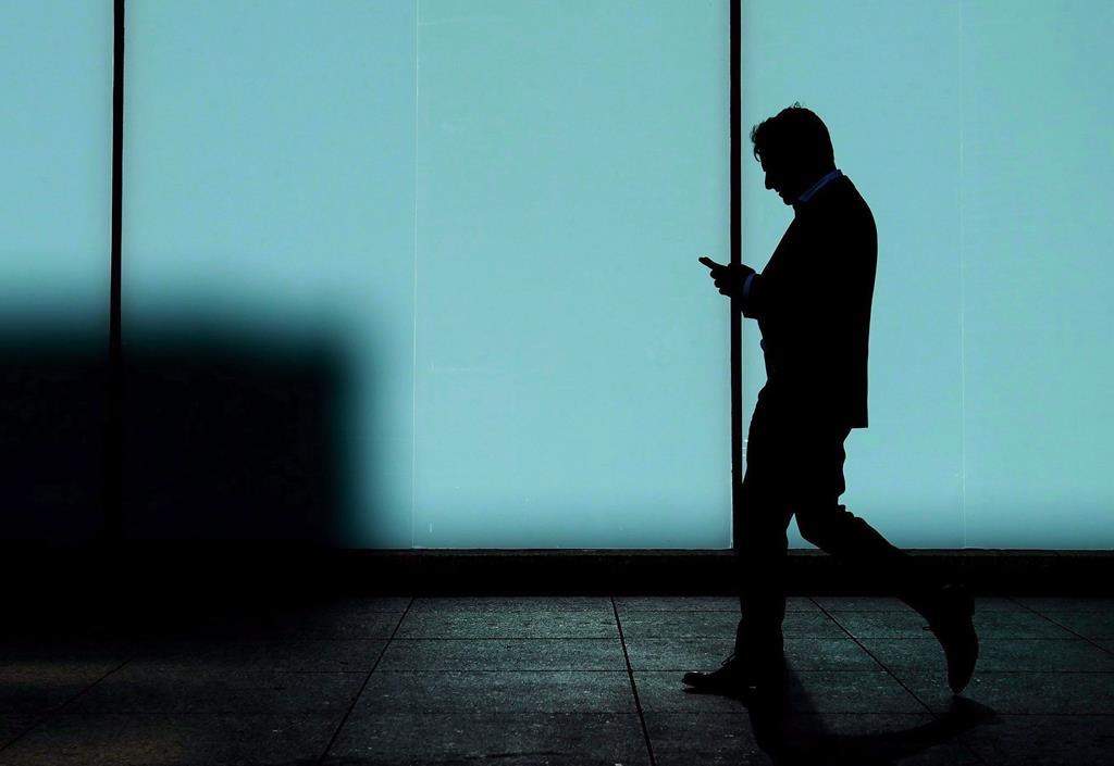 FILE - A man walks and texts on his smart phone in downtown Toronto, Monday, Oct. 30, 2017. THE CANADIAN PRESS/Nathan Denette.