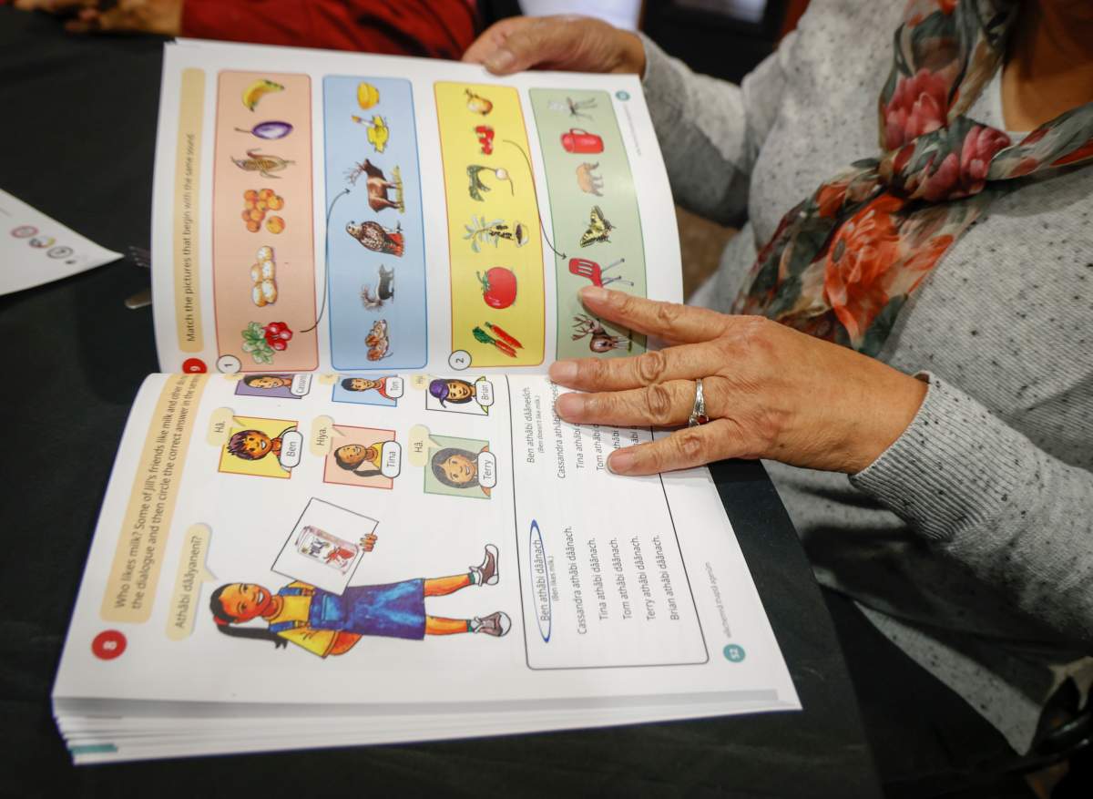 A woman holds open a book in an Indigenous language