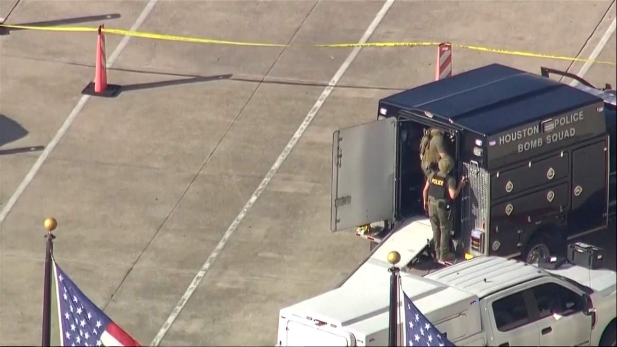 Members of the Houston Police Bomb Squad stand in a parking lot.