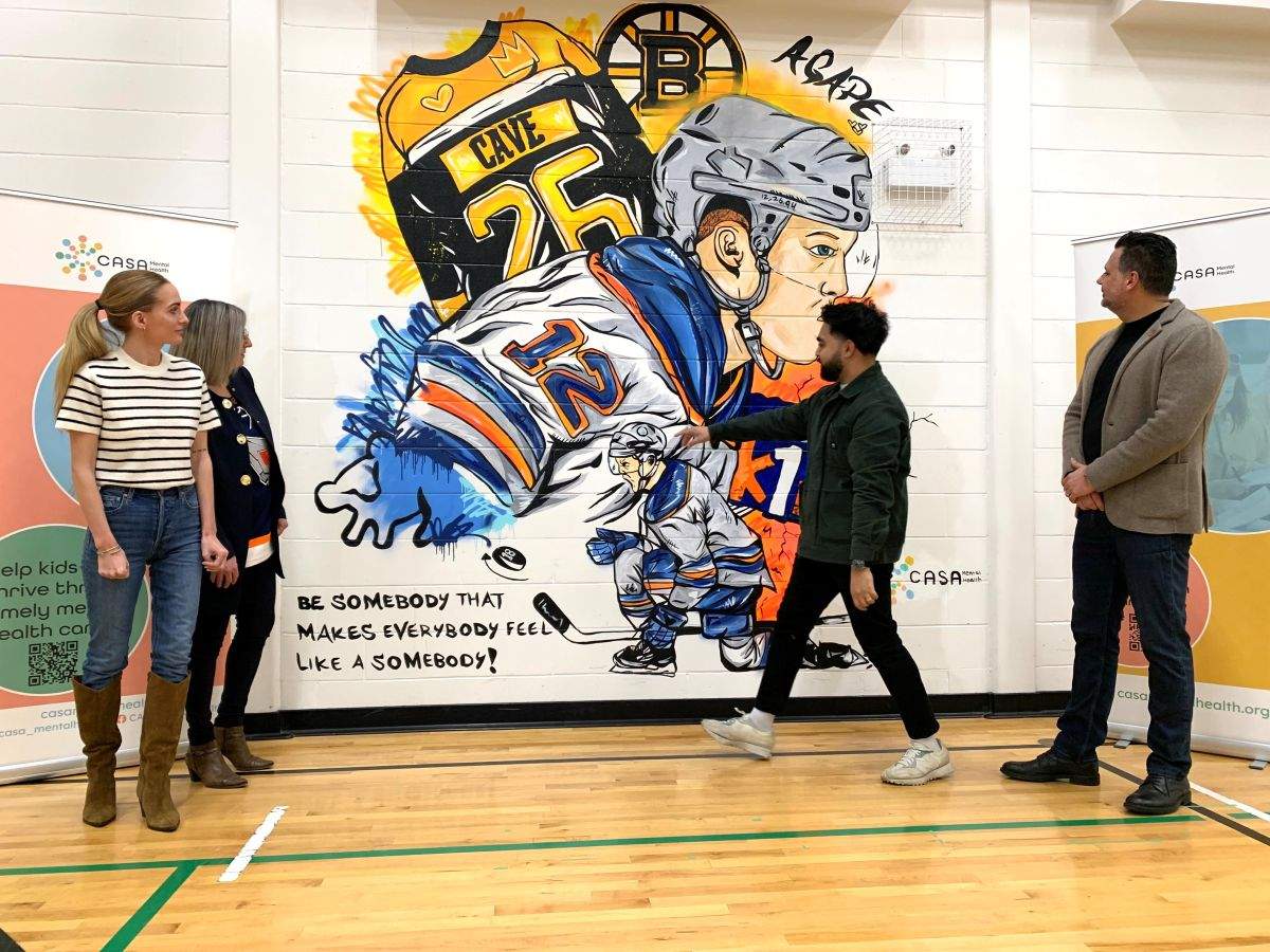 Artist Rahmaan Hameed shows Emily Cave a mural of her late husband Colby Cave at CASA House.