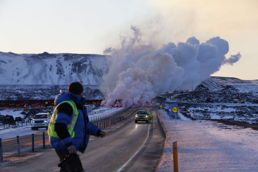 Emergency services close a road as lava erupts from a fissure on February 8, 2024 in Grandavik, Iceland.