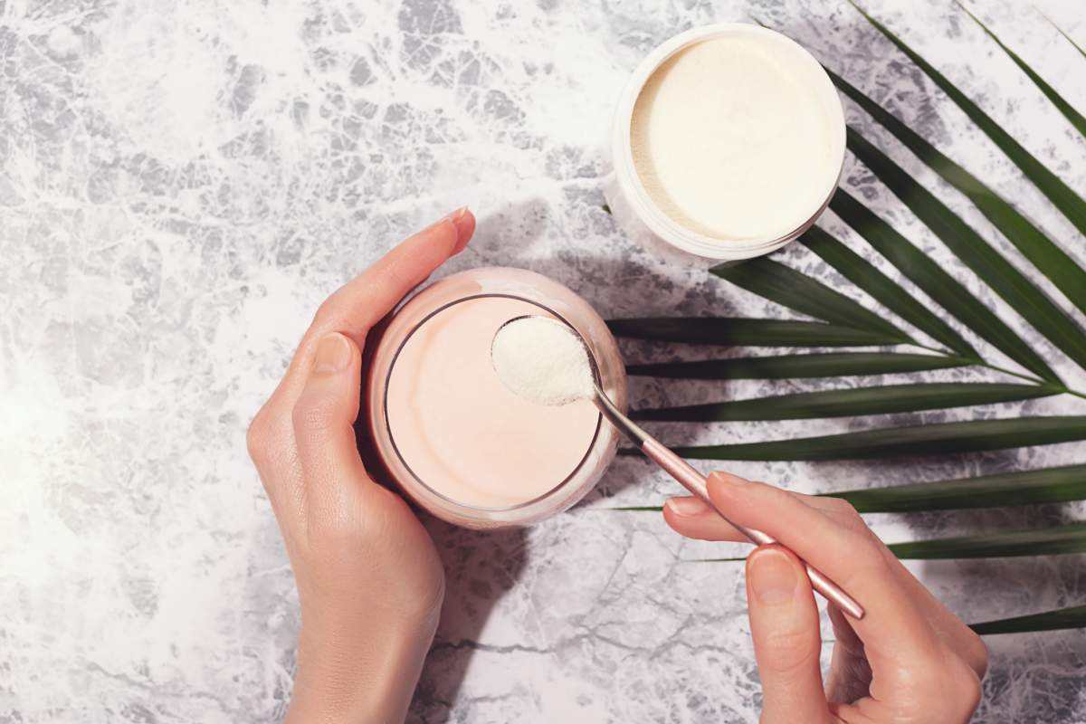 Woman pouring collagen powder in morning smoothie