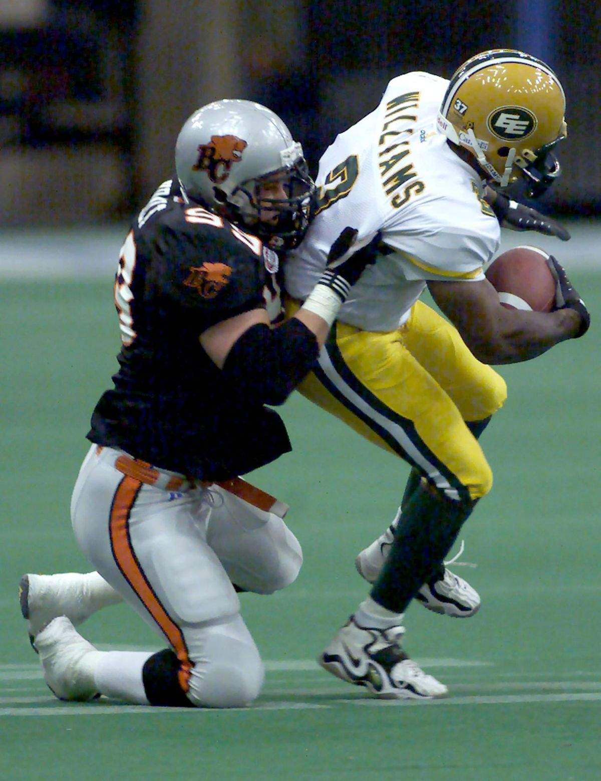 B.C. Lions Jason Kralt (99) gets a hold of Edmonton Eskimos Henry Williams (2) during a first half punt return in CFL action in Vancouver Saturday, Sept. 16, 2000.