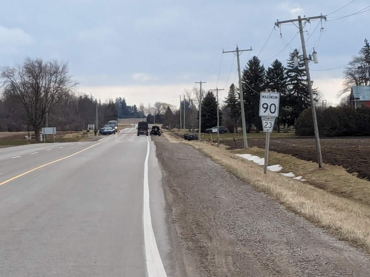 A stretch of rural road with vehicles in the distance.