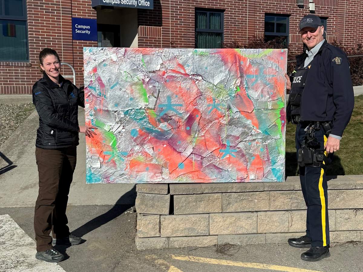Two people standing beside a recovered stolen painting.
