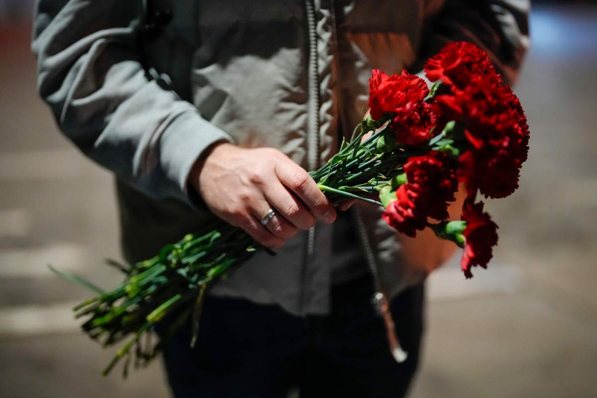 A Russian man holds a bunch of red carnations in Istanbul, Turkey, Friday, Feb. 16, 2024. Small groups of Russian nationals arrived at the Russian Consulate in Istanbul with flowers they intended to leave at the gate in honor of Alexei Navalny. Police however, turned them away, citing a government decree that bars protests at the busy pedestrian street where the mission is located. (AP Photo/Emrah Gurel)