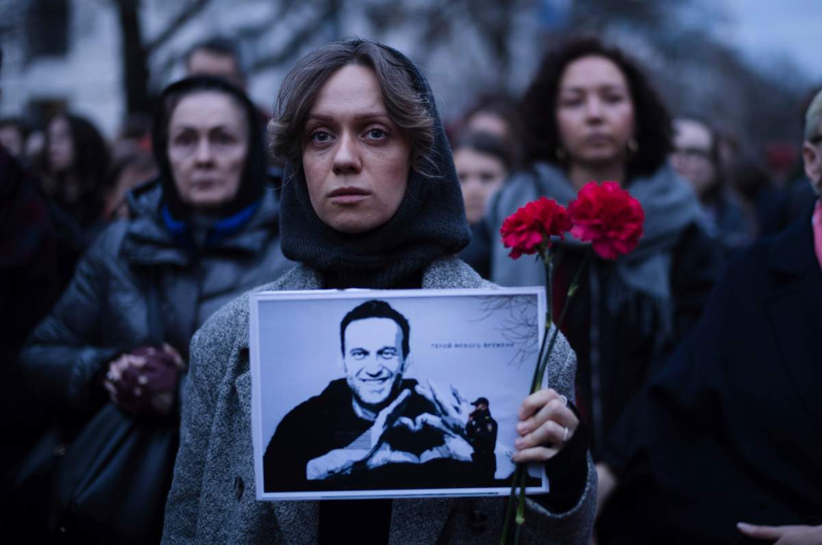A woman holds flowers and a portrait of opposition leader Alexei Navalny during a protest in front of the Russian embassy in Berlin, Germany, Friday, Feb. 16, 2024. Russia’s prison agency says that imprisoned opposition leader Alexei Navalny has died. He was 47. The Federal Prison Service said in a statement that Navalny felt unwell after a walk on Friday Feb. 16, 2024 and lost consciousness.(AP Photo/Markus Schreiber)