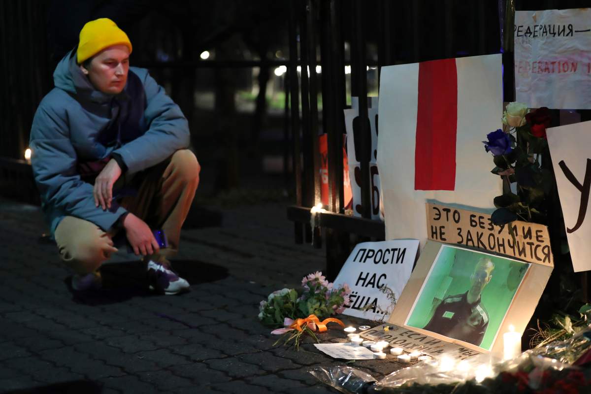 A man sits near a portrait of Russian opposition leader Alexei Navalny with the words reading “forgive us Alyosha (Alexei) This madness will not end” at the the fence of Russian Embassy in honor of Alexei Navalny in Yerevan, Armenia, Friday, Feb. 16, 2024. Russian authorities say that Alexei Navalny, the fiercest foe of Russian President Vladimir Putin who crusaded against official corruption and staged massive anti-Kremlin protests, died in prison. He was 47. (Vahram Baghdasaryan/PHOTOLURE via AP)