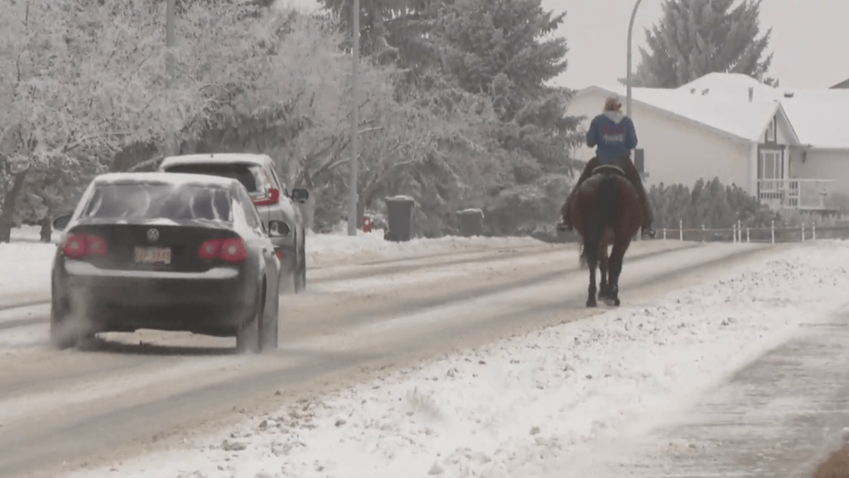 Shelby Opheim rides her horse Charlie down the streets of High River, Alta.