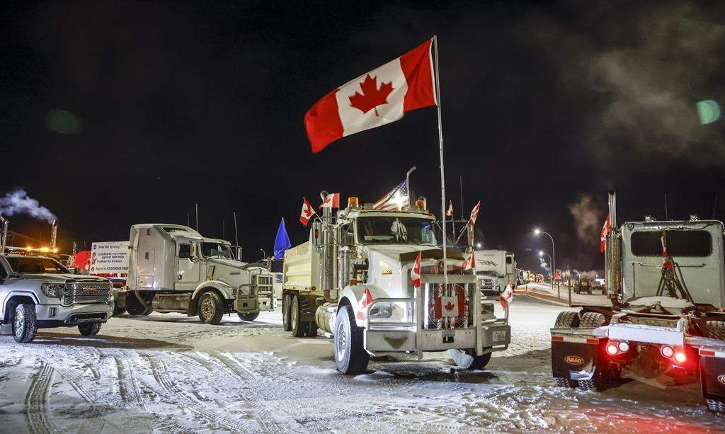 Anti-COVID-19 vaccine mandate demonstrators gather as a truck convoy blocks the highway at the U.S. border crossing in Coutts, Alta., Tuesday, Feb. 1, 2022. An internal RCMP review of the force's response to "Freedom Convoy" protests found that some officers at the scene of an Alberta blockade were not told of threats to harm police until after the episode ended. THE CANADIAN PRESS/Jeff McIntosh.