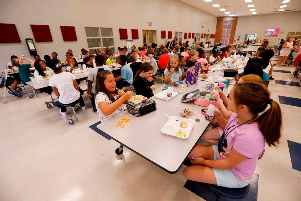 Half of a tangerine instead of a whole one, half of a hard-boiled egg or an apple cut six ways — student nutrition programs across Ontario are finding ways to stretch increasingly insufficient dollars. Students at Madison Crossing Elementary School in Canton, Miss., eat lunch in the school's cafeteria on Friday, Aug. 9, 2019. THE CANADIAN PRESS/AP-Rogelio V. Solis.