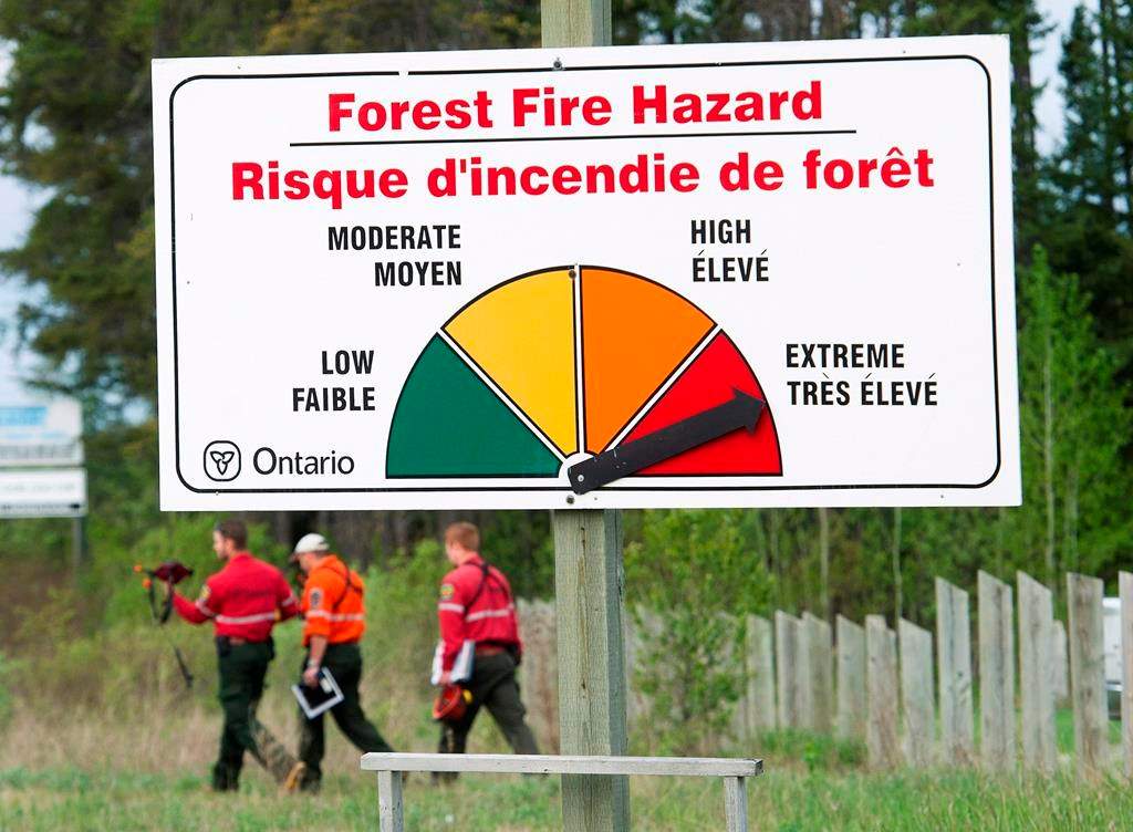 Fire rangers walk past a forest fire hazard sign west of Timmins, Ont., on May 26, 2012.