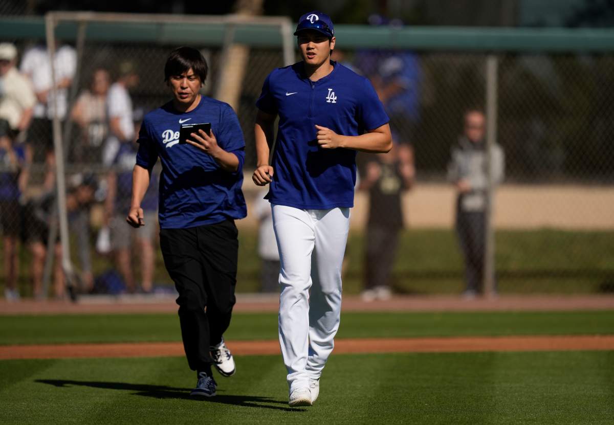 Los Angeles Dodgers' Shohei Ohtani, right, jogs on to a practice field with interpreter Ippei Mizuhara, left, as he arrives for spring training baseball workouts at Camelback Ranch in Phoenix, Sunday, March 3, 2024, in Phoenix.