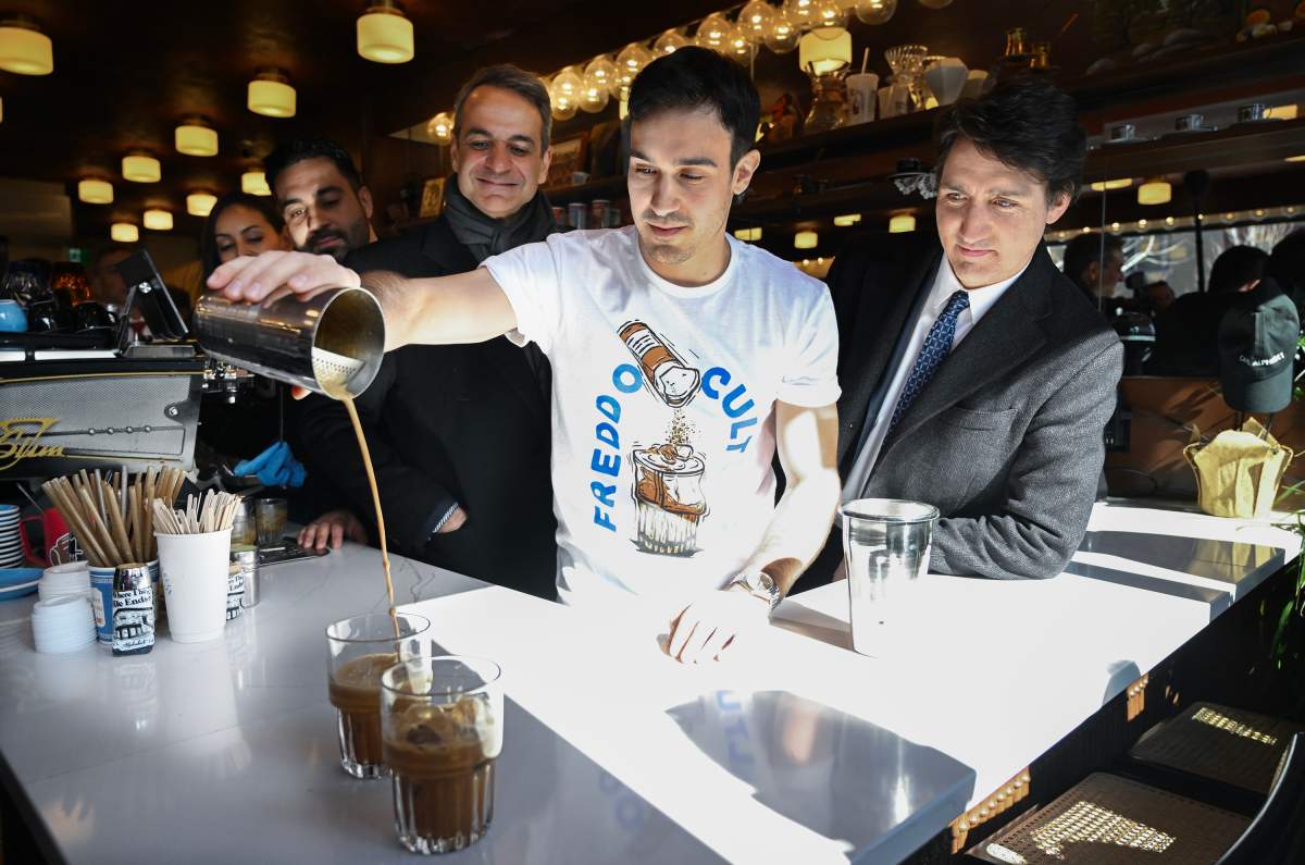 Prime Minister Justin Trudeau, right, and Prime Minister of Greece Kyriakos Mitsotakis, left, look on as Tom Argiropoulos prepares a freddo cappuccino during a visit to Cafe Alphabet in Montreal, Sunday, March 24, 2024. THE CANADIAN PRESS/Graham Hughes