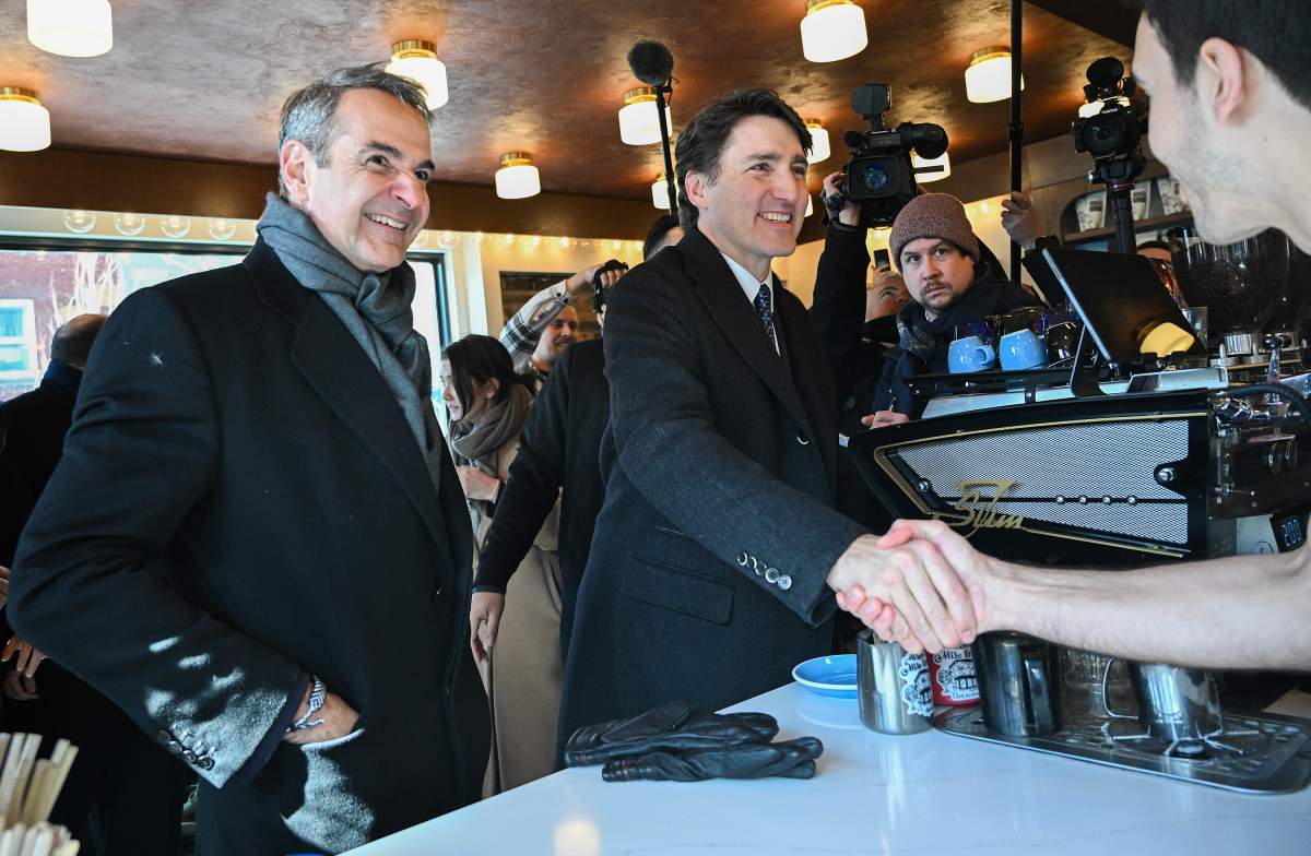 Prime Minister Justin Trudeau, right, and Prime Minister of Greece Kyriakos Mitsotakis greet Tom Argiropoulos, right, during a visit to Cafe Alphabet in Montreal, Sunday, March 24, 2024. THE CANADIAN PRESS/Graham Hughes