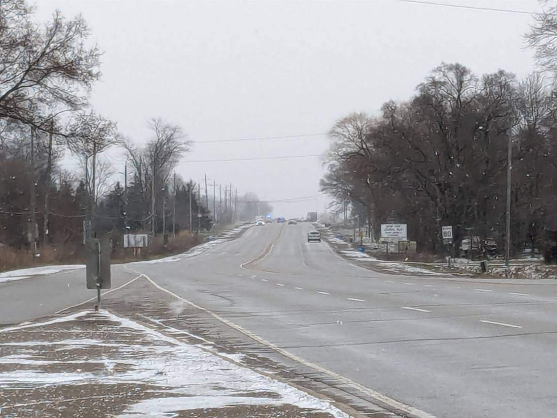 Emergency vehicles seen in the distance from a snowy road.