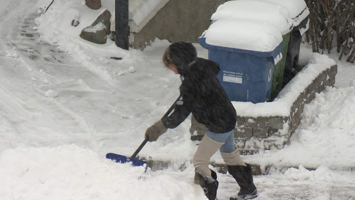 A Calgarian clears snow on March 20, 2024.