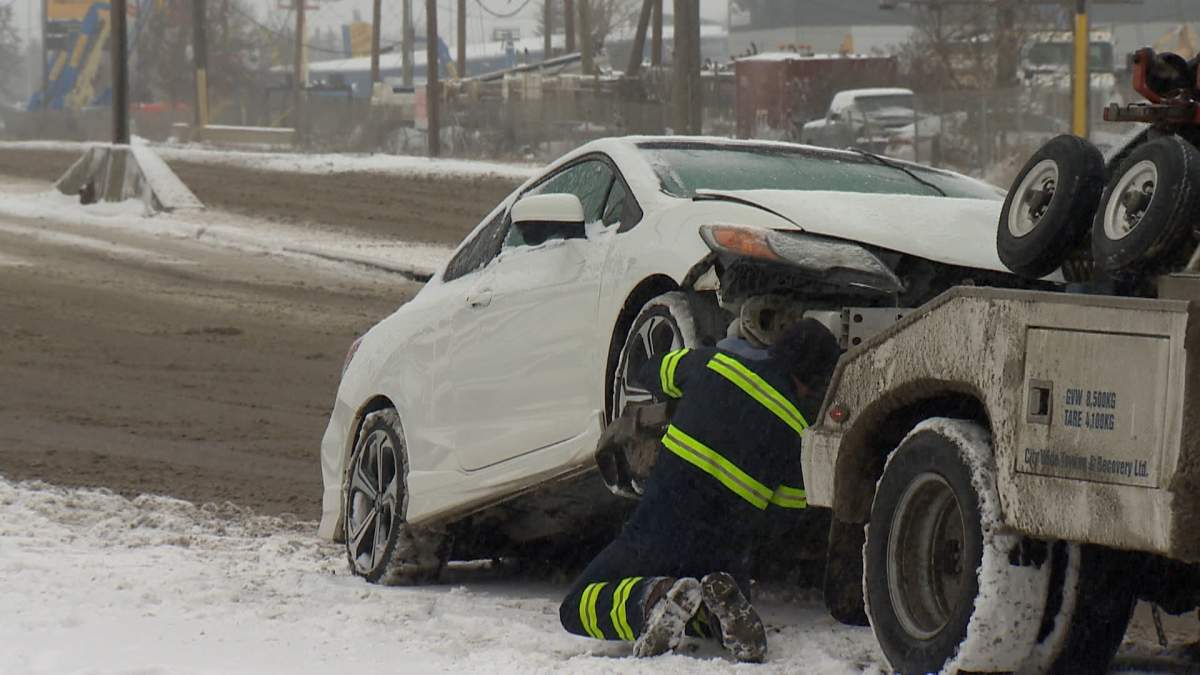 A tow truck driver hooks up a car after a collision on March 20, 2024.